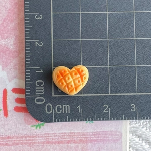 Detailed view of mini orange heart waffle resin charm on a grid cutting mat for sizing