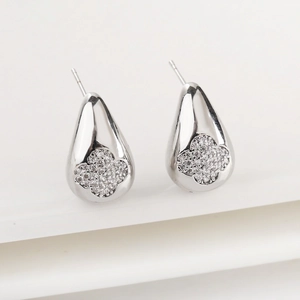 Macro shot of silver teardrop earrings with clover-shaped cubic zirconia inlay