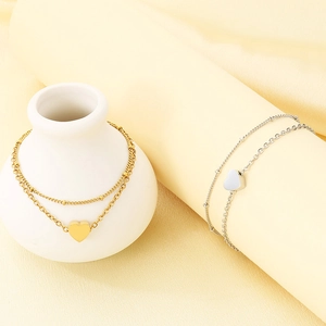 Nahaufnahme doppellagiger Herz-Fußkettchen in Gold und Silber mit eleganten Anhängern