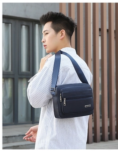 Detail view of navy blue nylon crossbody bag with multiple zip pockets and adjustable strap