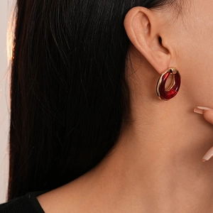 Detail of red resin round earrings with gold fasteners worn by a fashion model