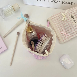 Spacious pink checkered fabric makeup bag with bow detail showing cosmetic storage capacity