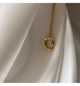 Detailed close-up of golden oval donut pendant on silk background for high-end look