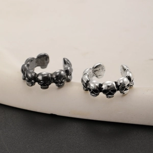 Close-up of gothic skull ear cuffs in vintage silver and black metallic finish