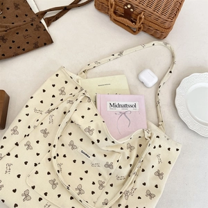 Detail of off-white corduroy tote with heart patterns and lifestyle accessories
