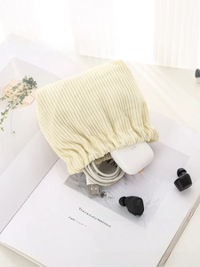 Detail view of corduroy mini pouch holding USB cable and TWS earphones for storage