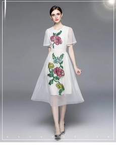 Détails de broderies florales colorées et mesh à pois sur une élégante robe midi blanche