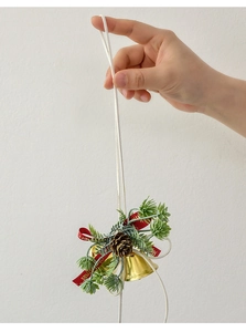 Detail of gold Christmas bells with pine cones and Merry Christmas ribbon held by hand