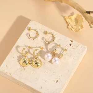 Détail de trois boucles d'oreilles perles plaquées or et zircons sur socle en pierre