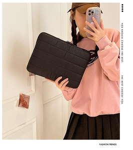Mirror selfie showing the scale of a black quilted laptop sleeve with horizontal stitching