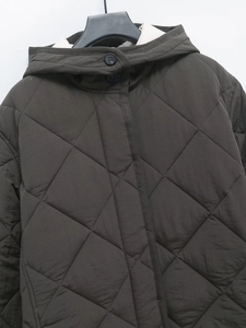 Close-up of deep olive green quilted jacket showing stitching details and button closure