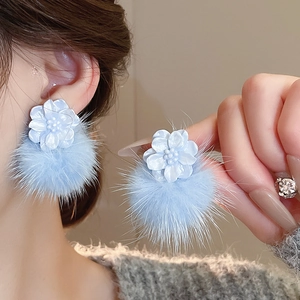 Detail of light blue resin flower earring with a fluffy fur pompom for winter styling