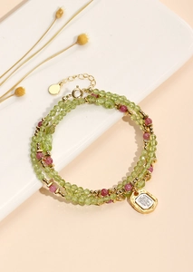 Detailed macro of multi-layer beaded necklace with green crystals and a gold square pendant