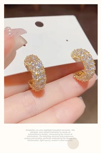 Detail of gold C-shaped earrings with micro-pave white zircon stones for women