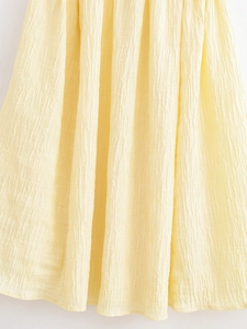 Detail of light yellow tree texture pleated fabric with delicate vertical draping effect