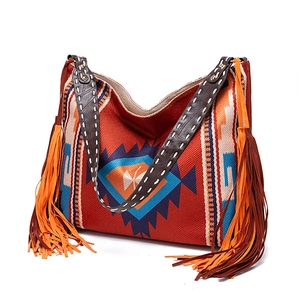 Detailed view of colorful bohemian woven tote bag featuring long brown fringe and leather strap