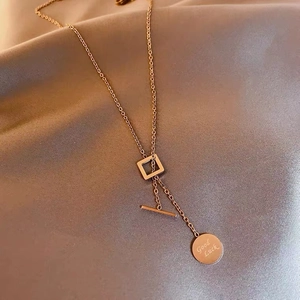 Detailed shot of gold titanium necklace with Good Luck round pendant on grey silk fabric
