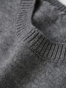 Detailed close-up of the ribbed neckline and fine knit texture on a dark grey sweater