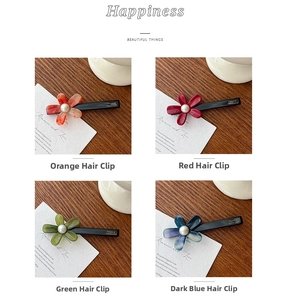 Detail of four acetate flower hair clips with pearls on a wooden desk background