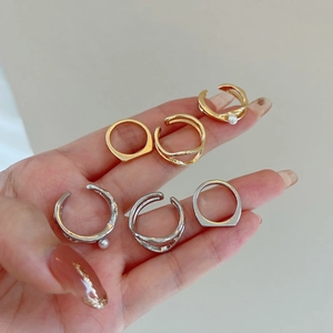 Detail shot of six gold and silver geometric rings with pearls on model's hand