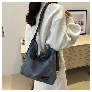 Detail of blue-grey canvas tote bag showing side pocket and adjustable brown strap