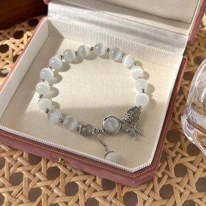 Detail of beaded bracelet featuring opal cat eye stones and silver butterfly charm