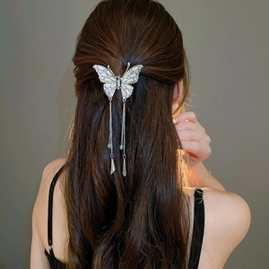 Pince à cheveux papillon argentée avec glands et strass sur de longs cheveux bouclés