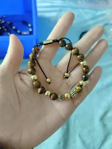 Detail of 8mm tiger eye beads and pavé crystal charms on adjustable woven bracelet