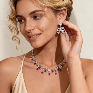Close-up of elegant silver bow earrings and necklace set with red teardrop gemstones