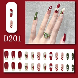 Detail of Christmas press-on nails with 3D bows, red checkerboard, and heart patterns