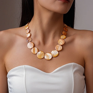 Close-up of shell disc necklace with warm amber and pearlescent gradients on a model