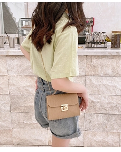 Brown woven crossbody chain bag with golden metal lock shown on a model's shoulder