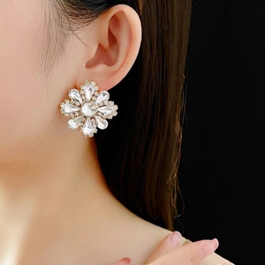 Sparkling crystal flower stud earrings with silver-toned base on model with black background