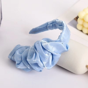 Macro detail of a light blue pleated satin headband with sparkling rhinestones decoration