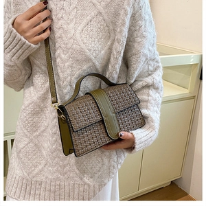 Detail of retro woven texture and gold buckle on a brown and olive green crossbody bag