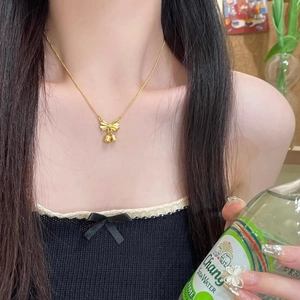 Elegant gold bow lily of the valley pendant necklace shown on a model's collarbone