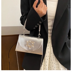 Detail of silver metallic handbag with crystal buckle and elegant chain shoulder strap
