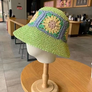 Detailed close-up of handmade floral crochet pattern on a green straw sun hat