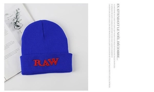 Detail of royal blue beanie featuring a red RAW embroidery and ribbed knit texture