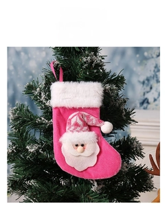 Détail d'une chaussette de Noël rose avec poupée Père Noël suspendue au sapin enneigé