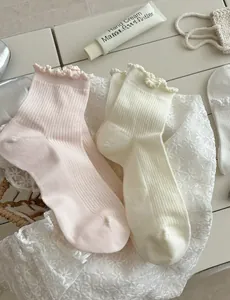 Detail of lettuce edge knit cotton socks in soft pink and cream white colors