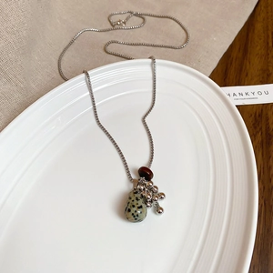 Detail of tiger eye stone tassel necklace with spotted stone beads on white tray