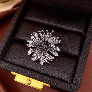 Detailed close-up of a vintage sunflower brooch with black rhinestones on dark velvet