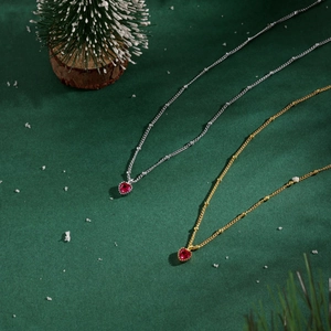 Detail of gold and silver necklaces with red heart pendants in festive scenery