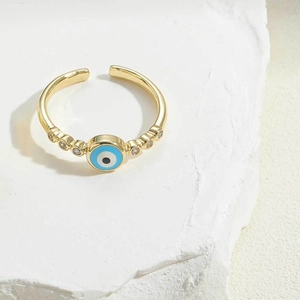 Close-up of golden evil eye ring with blue enamel and sparkling zircon accents