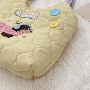 Detail of yellow quilted tote bag featuring cute animal embroidery and colorful buttons
