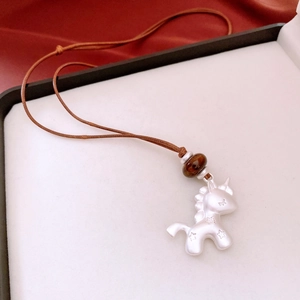 Vue détaillée du pendentif licorne avec relief d'étoile et cordon tressé sur soie rouge