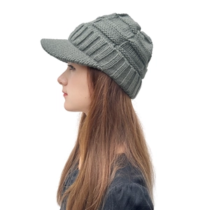 Vue latérale d'un bonnet tricoté gris-vert avec visière et motifs de tissage variés