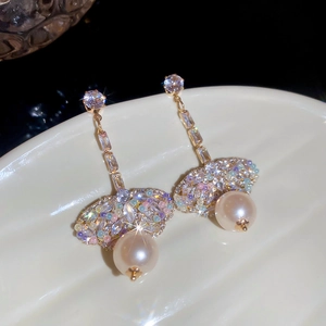 Macro shot of elegant gold tassel earrings with pearls and crystals on ceramic base