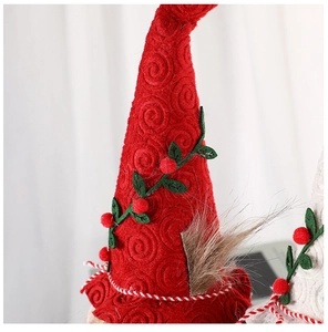 Detail der roten Spiral-Plüschstruktur am Weihnachtswichtelhut mit Beeren und Blättern